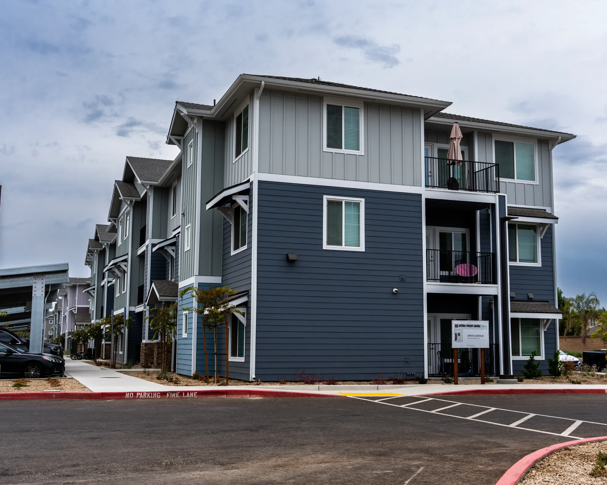 Three-story apartment building at 695 D Street painted slate gray with white trim