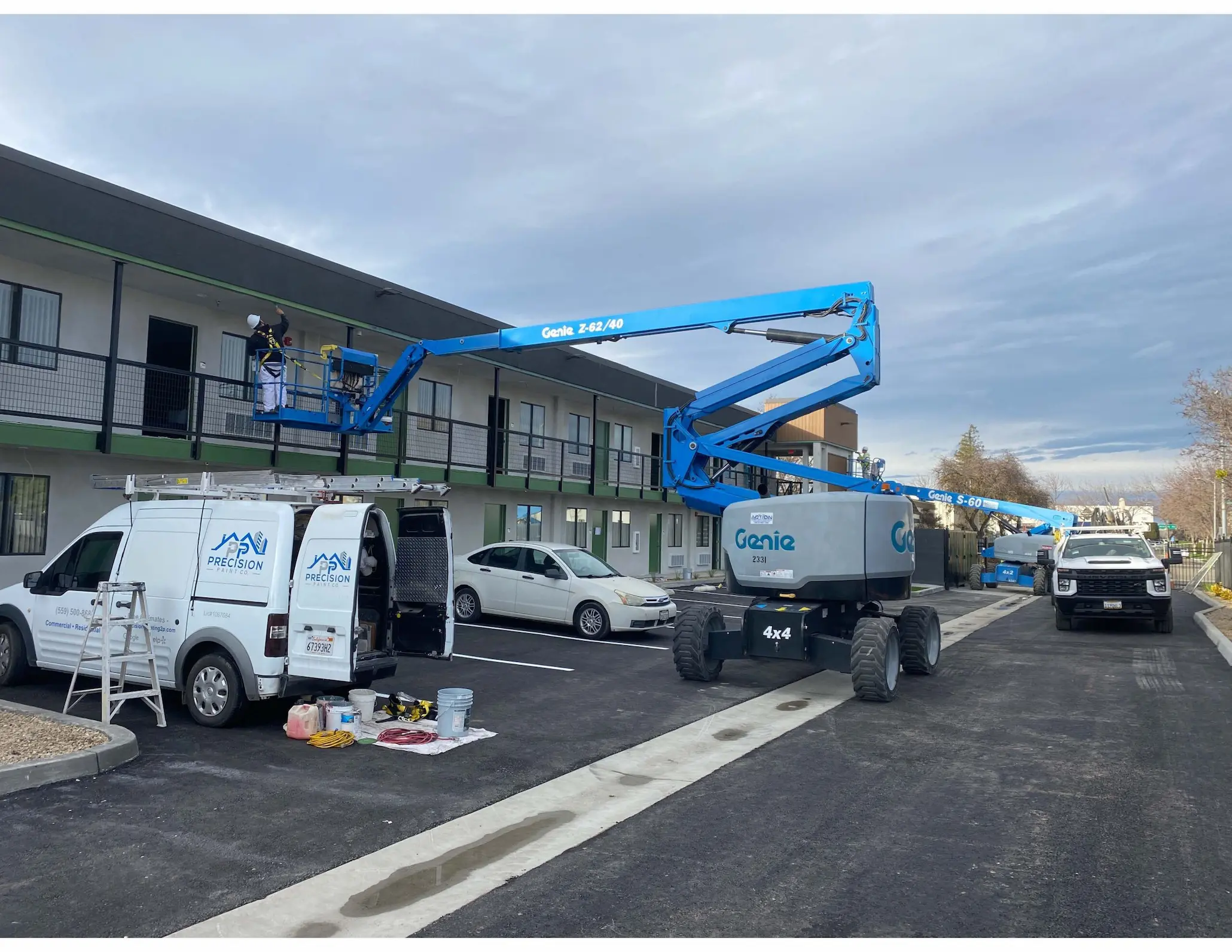 Two-story hospitality property exterior repaint with lifts and work vans