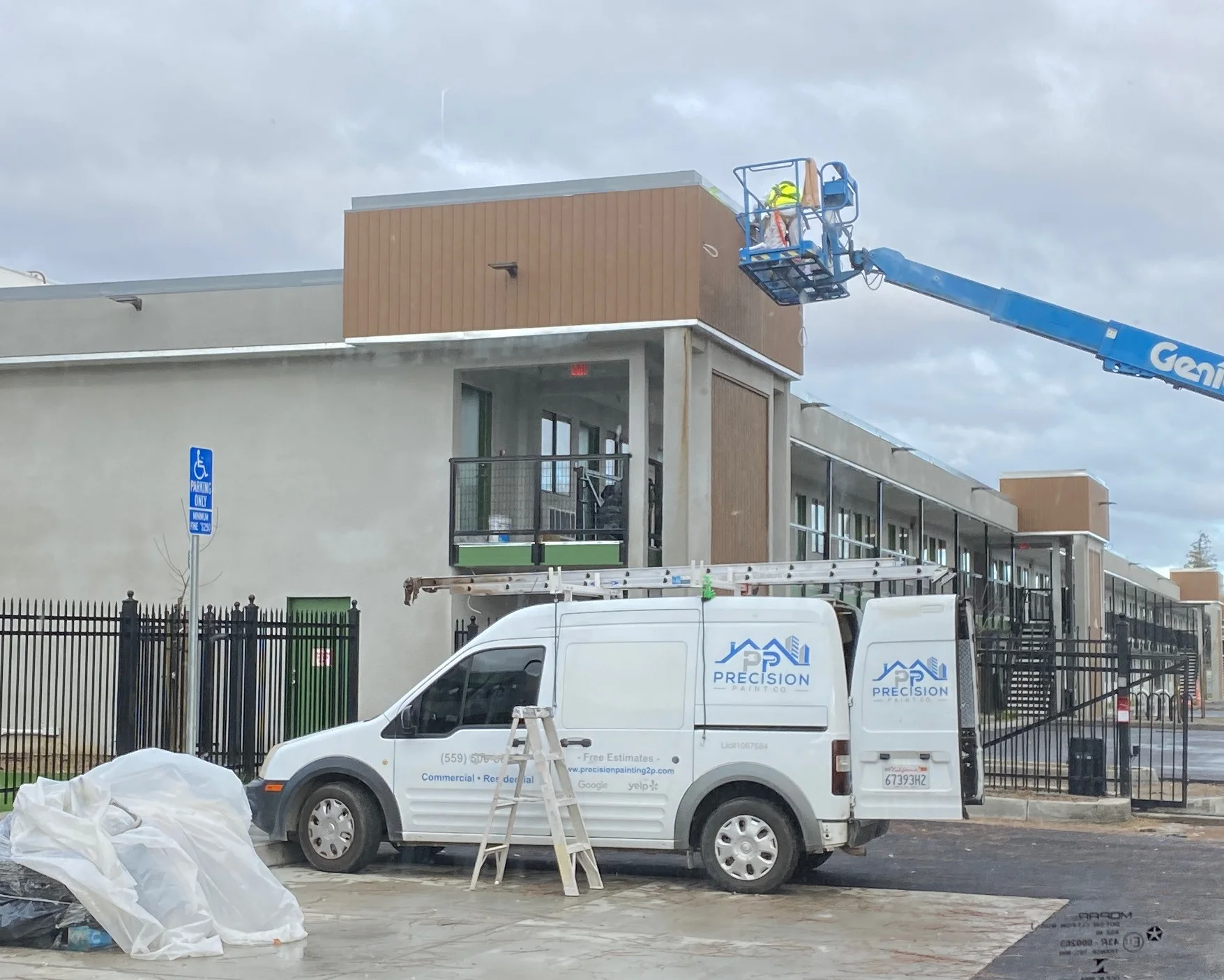 Commercial retail building being repainted from a boom lift