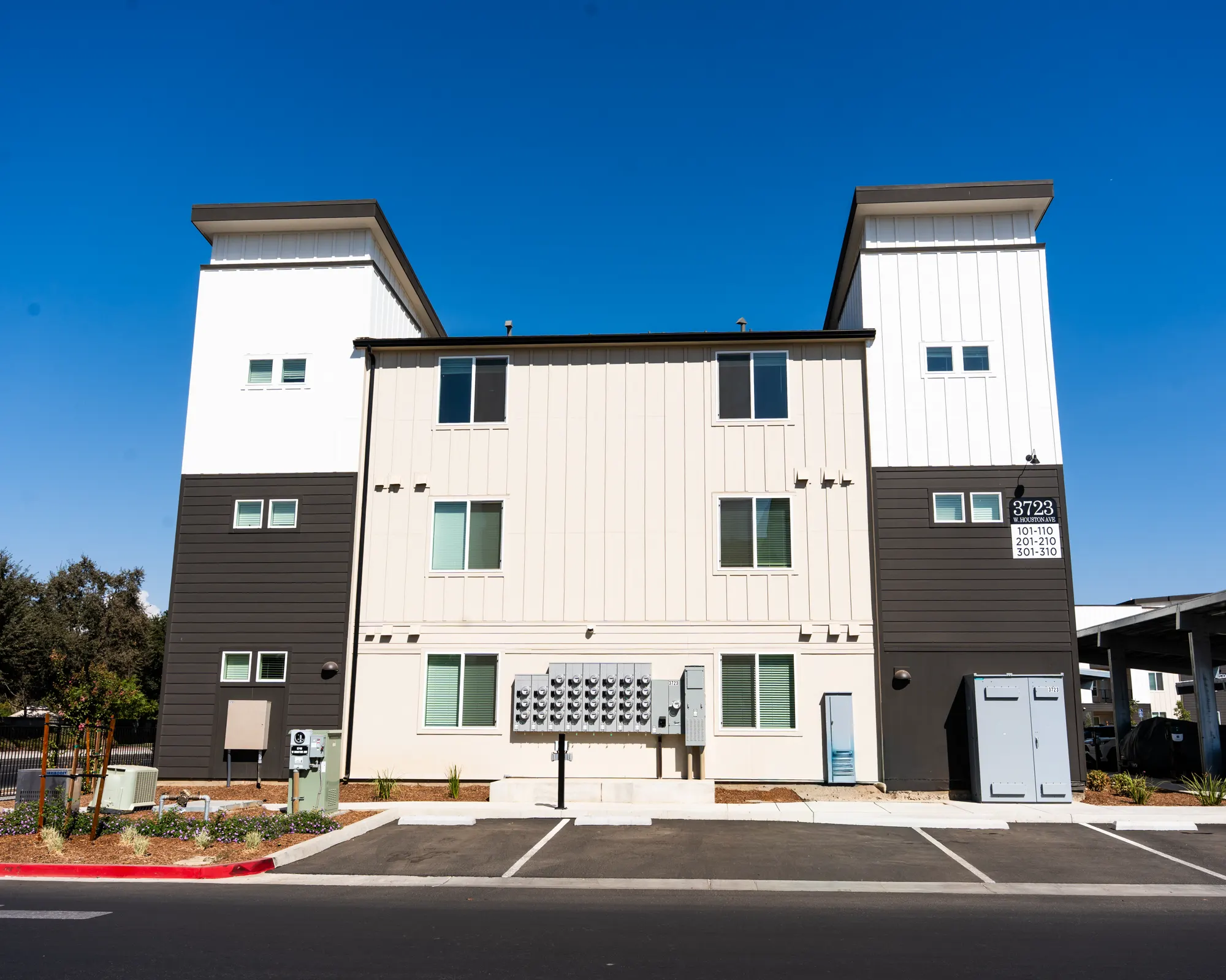 Front elevation of a Demaree Apartments building painted white and charcoal